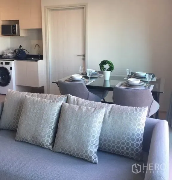 คอนโด ให้เช่าในHuai Khwang, Bangkok - ครัวแบบเปิดมีเครื่องซักผ้า และโต๊ะอาหารกระจก 4 ที่นั่งข้างโซฟา