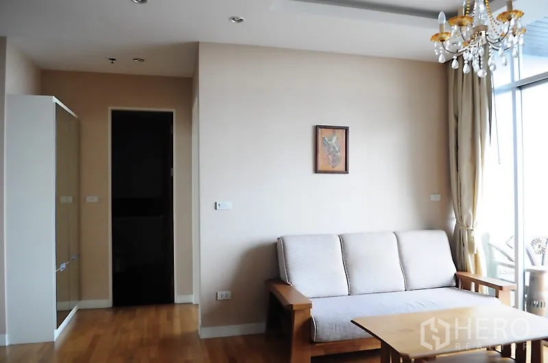 Condominium for rent in Pathum Wan, Bangkok - Bright living room with sofa, crystal chandelier, wood floors and large glass wall.