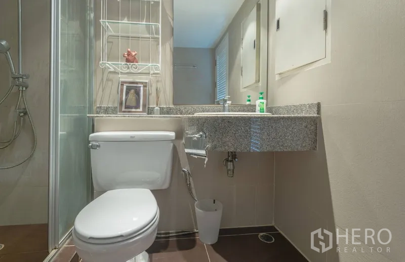 Condominium for rent in Pathum Wan, Bangkok - Modern bathroom with glass shower, granite vanity and toilet.
