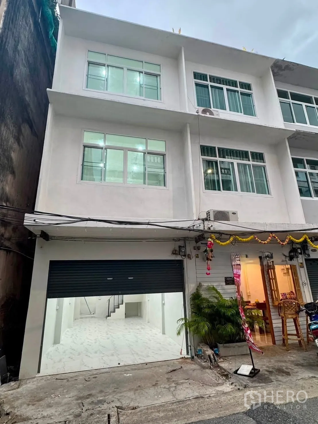 Shophouse for rent in Sathon, Bangkok - Three-storey white shophouse exterior with wide roller shutter and large windows.