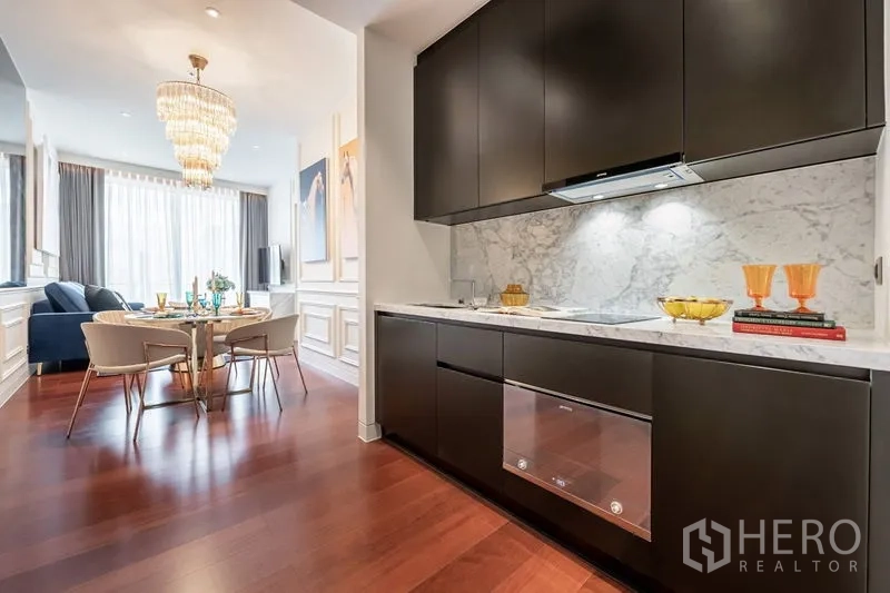 คอนโด ให้เช่าในWatthana, Bangkok - ครัวบิลต์อินโทนเข้ม ผนังหินอ่อน พื้นไม้ ต่อเนื่องสู่พื้นที่ทานอาหารพร้อมโคมระย้า