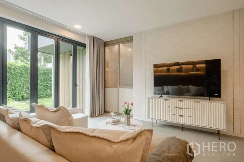 Detached House for rent in Saphan Sung, Bangkok - Living room with TV console and sliding doors opening to the garden.