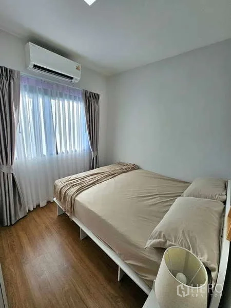 Townhouse for rent in Bang Phli, Samut Prakan - Cozy double bedroom with air conditioning, curtains and wood flooring.