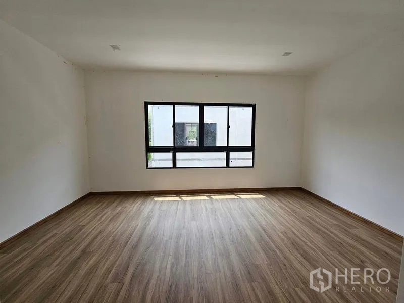 联排别墅 出租在Bang Kapi, Bangkok - 宽敞卧室，木纹地板，横向大窗引入自然光。