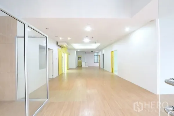 办公空间 出租在Bang Na, Bangkok - 明亮开放的走道，木质地板、嵌入式照明与玻璃隔间。