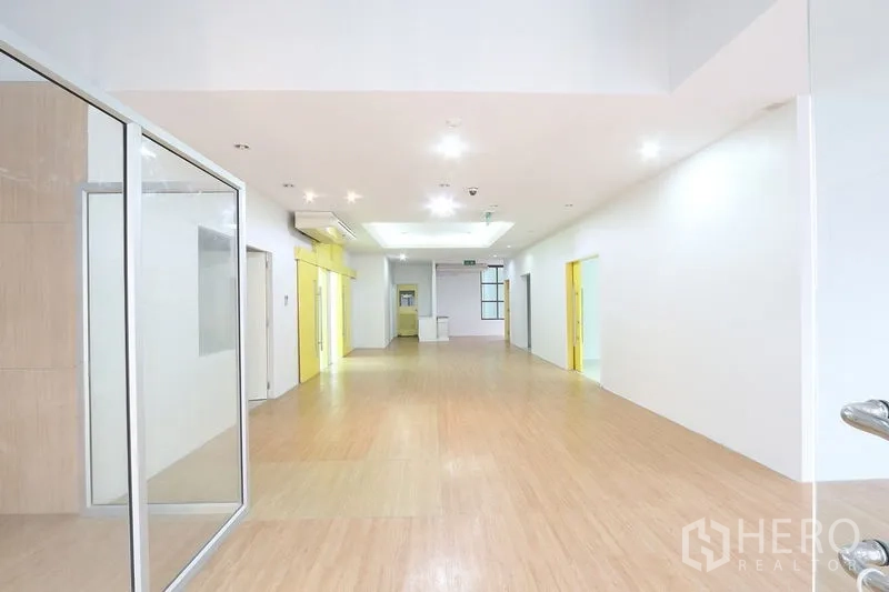 办公空间 出租在Bang Na, Bangkok - 明亮开放的走道，木质地板、嵌入式照明与玻璃隔间。