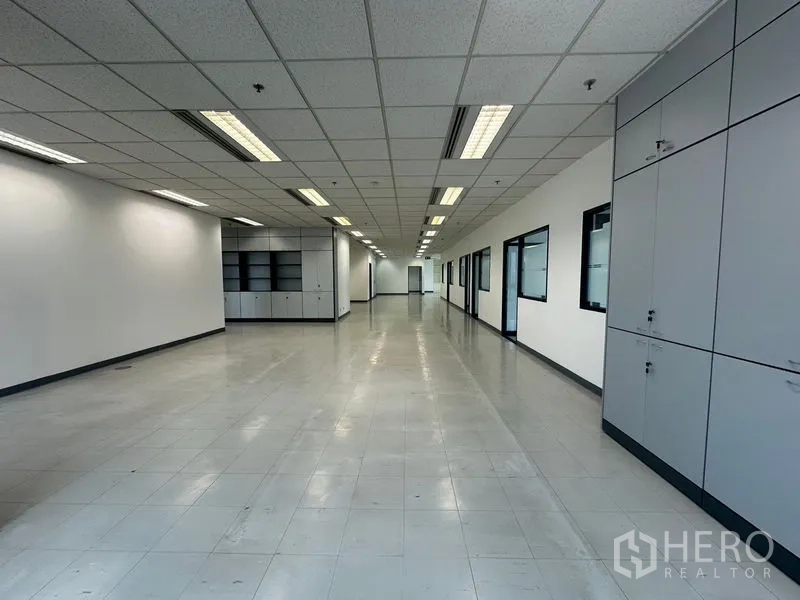 Office Space for rent in Khlong Toei, Bangkok - Open-plan workspace with ceiling lighting and storage cabinets at the far end.