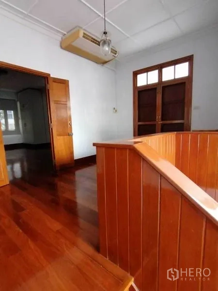Detached House for rent in Pathum Wan, Bangkok - Upper landing with polished wood balustrade, double wooden doors and ceiling light with wall A/C.