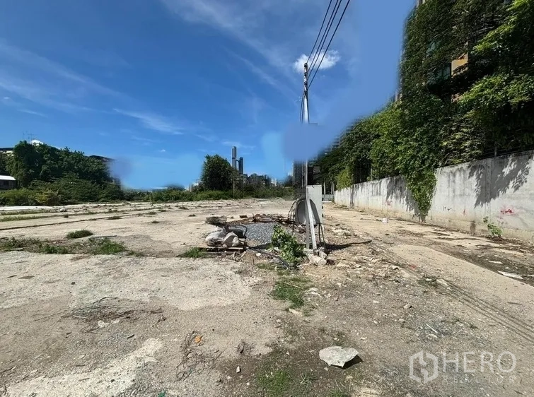 ที่ดิน ให้เช่าในKhlong Toei, Bangkok - แปลงที่ดินโล่ง พื้นคอนกรีต เสาไฟ และกำแพงรั้ว ใต้ท้องฟ้าสีฟ้า ย่านเอกมัย