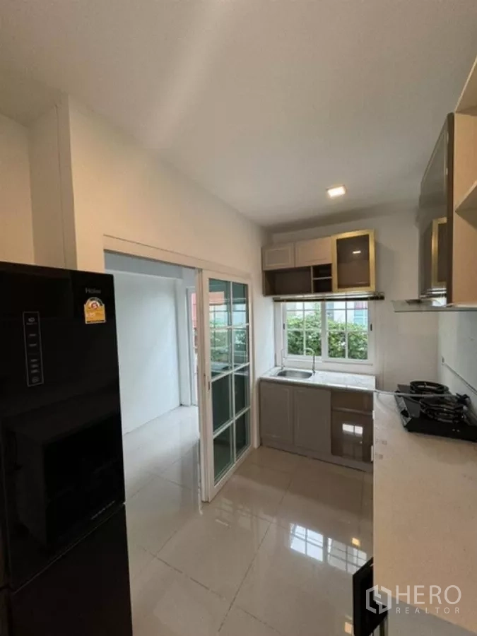 Detached House for rent in Thanyaburi, Pathum Thani - Kitchen from another angle with sliding glass door to the utility area.