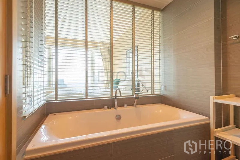 Condominium for sale in Khlong Toei, Bangkok - Large soaking bathtub with window blinds looking into the bedroom.