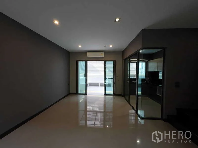 联排别墅 出租或出售在Lat Phrao, Bangkok - 客厅，亮面地砖，推拉门连阳台与玻璃隔断房。