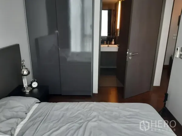 คอนโด ให้เช่าในKhlong Toei, Bangkok - ห้องนอนพร้อมตู้เสื้อผ้าบิวท์อินเงา โต๊ะข้างเตียงพร้อมโคมไฟ และประตูเปิดเชื่อมห้องน้ำในตัว