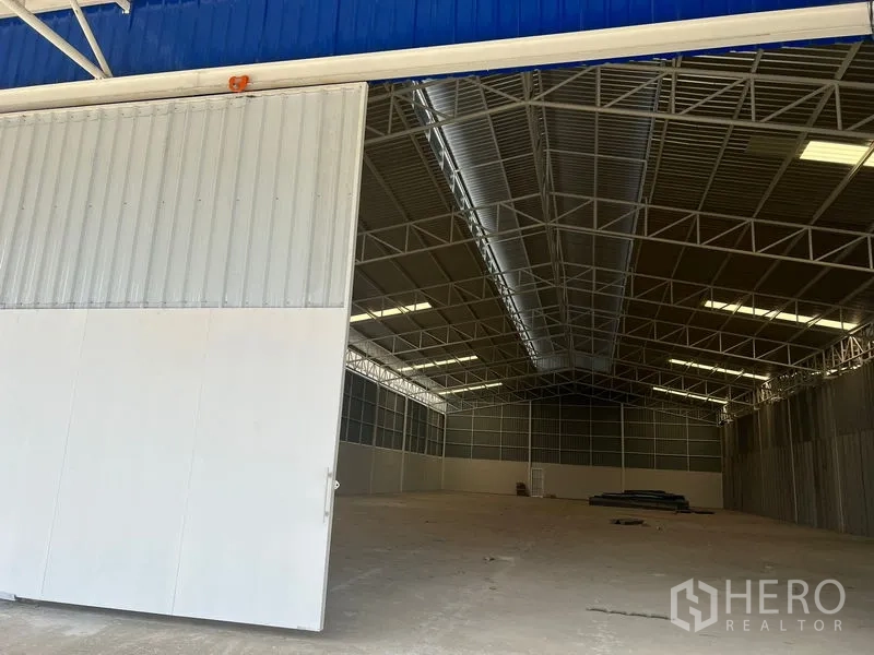 Warehouse for rent in Min Buri, Bangkok - Partially opened oversized sliding door revealing the bright warehouse interior.