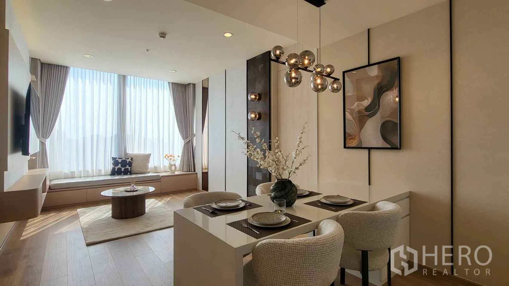 公寓 for sale in Watthana, Bangkok - 客厅区域带窗边座位、圆形茶几、现代吊灯与中性色调。