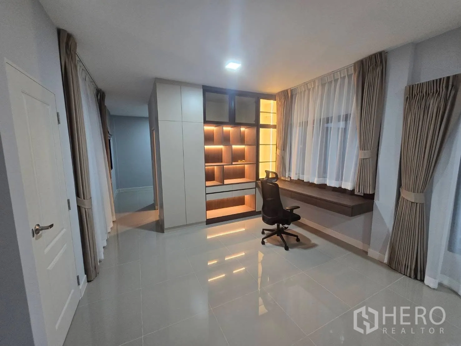Semi-detached House for rent in Bang Phli, Samut Prakan - Upstairs study area with built-in illuminated shelves, desk, and large windows.