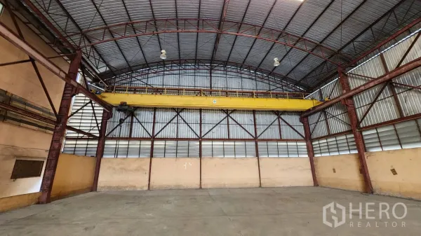 货栈 出租在Nonthaburi - 仓库端墙，可见黄色桥式行车与钢结构。