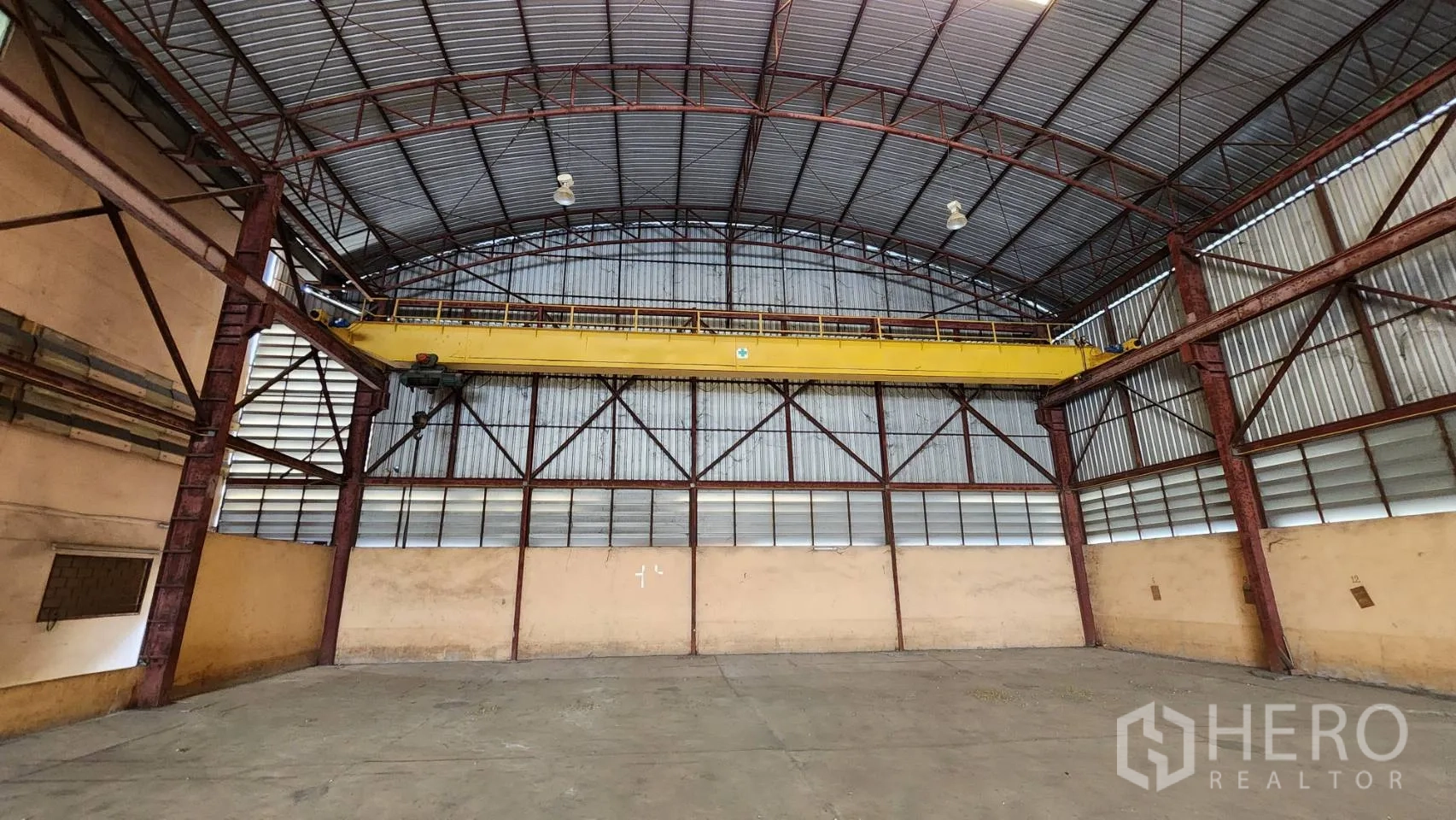 货栈 出租在Nonthaburi - 仓库端墙，可见黄色桥式行车与钢结构。