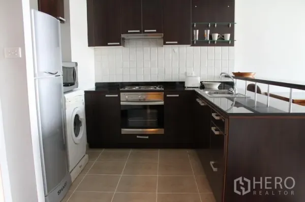 房间 出租在Bang Rak, Bangkok - 深色木质橱柜的现代厨房，配内置烤箱、冰箱和洗衣机。