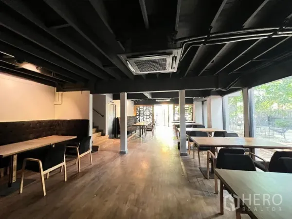 零售空间 出租在Bangkok - 用餐空间，黑色外露天花、木地板，落地窗临园景。