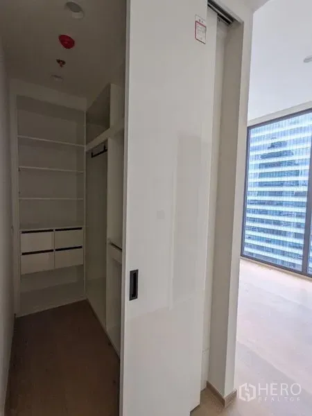 Condominium for sale - Walk-in closet with shelves and hanging space behind a sliding door beside the bedroom.