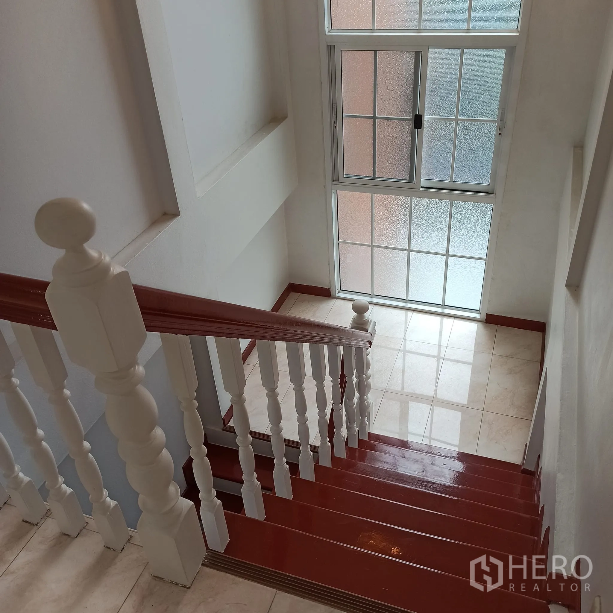 Townhouse for rent in Wang Thonglang, Bangkok - Wood staircase with white balusters beside a large frosted window.