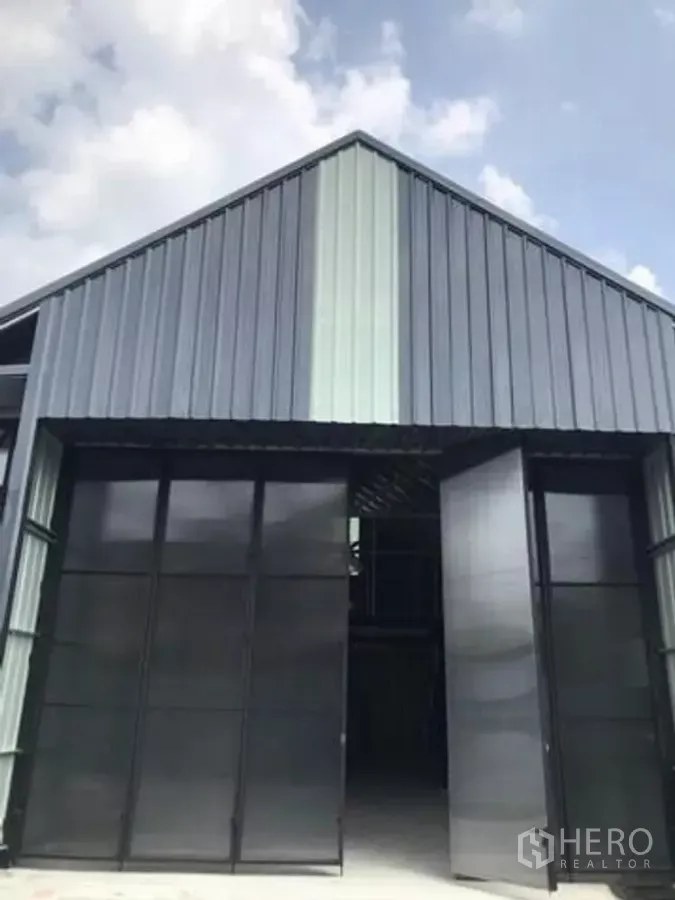 货栈 出租在Chatuchak, Bangkok - 金属外墙人字屋顶的现代仓库立面，宽幅推拉门打开。
