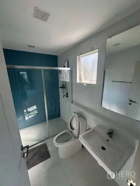 独立式住宅 出租在Prawet, Bangkok - 客卫配推拉玻璃淋浴间、蓝色点缀墙与台盆柜。