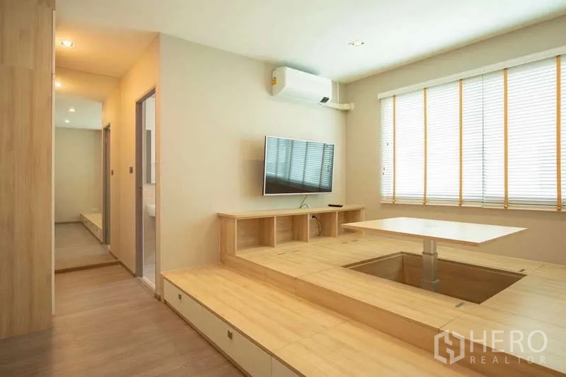 联排别墅 出租或出售在Lat Phrao, Bangkok - 采光充足的客厅，日式抬高地台、升降桌、壁挂电视与百叶窗。