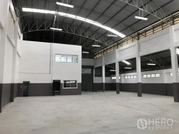 Factory for rent in Pathum Thani - Spacious warehouse interior with mezzanine office and large roller shutter.