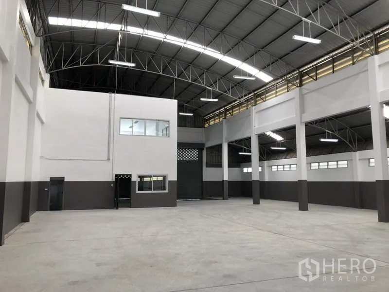 Factory for rent in Pathum Thani - Spacious warehouse interior with mezzanine office and large roller shutter.