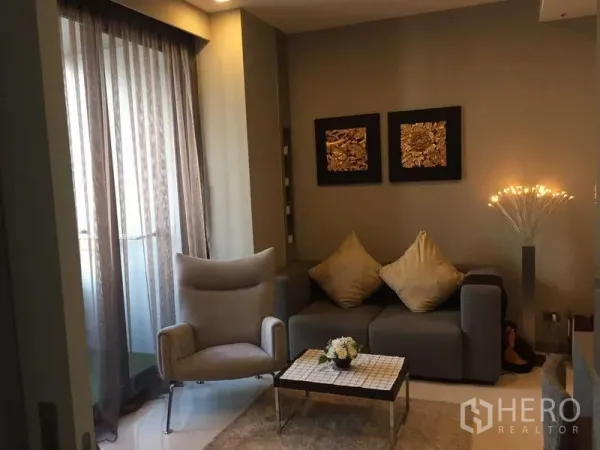 Condominium for rent in Bang Rak, Bangkok - Cozy living room at M Silom with grey sofa, accent chair and balcony window with sheer curtains.