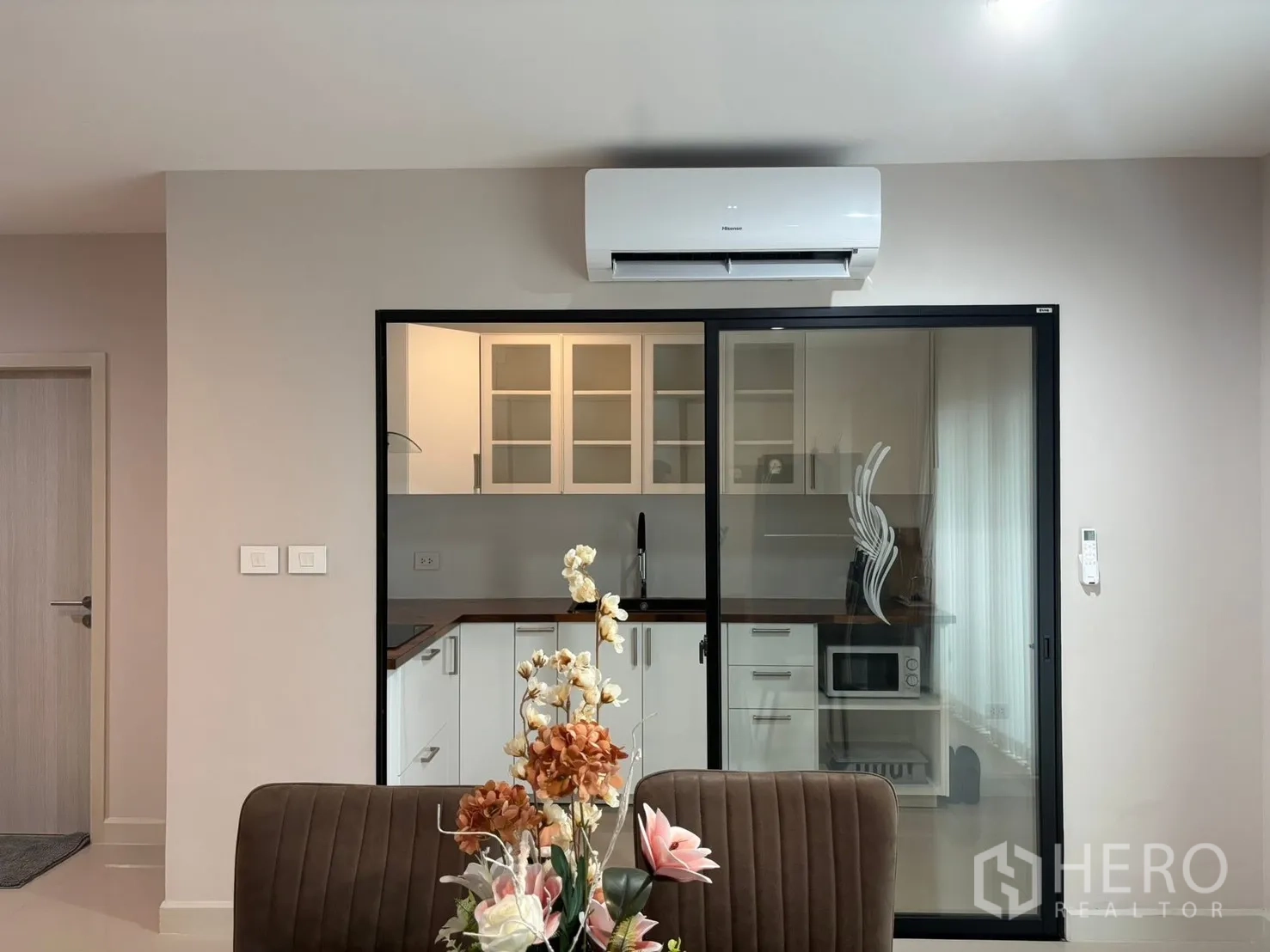 Townhouse for rent in Saphan Sung, Bangkok - Kitchen view from the dining area with sliding glass partition and air conditioner.