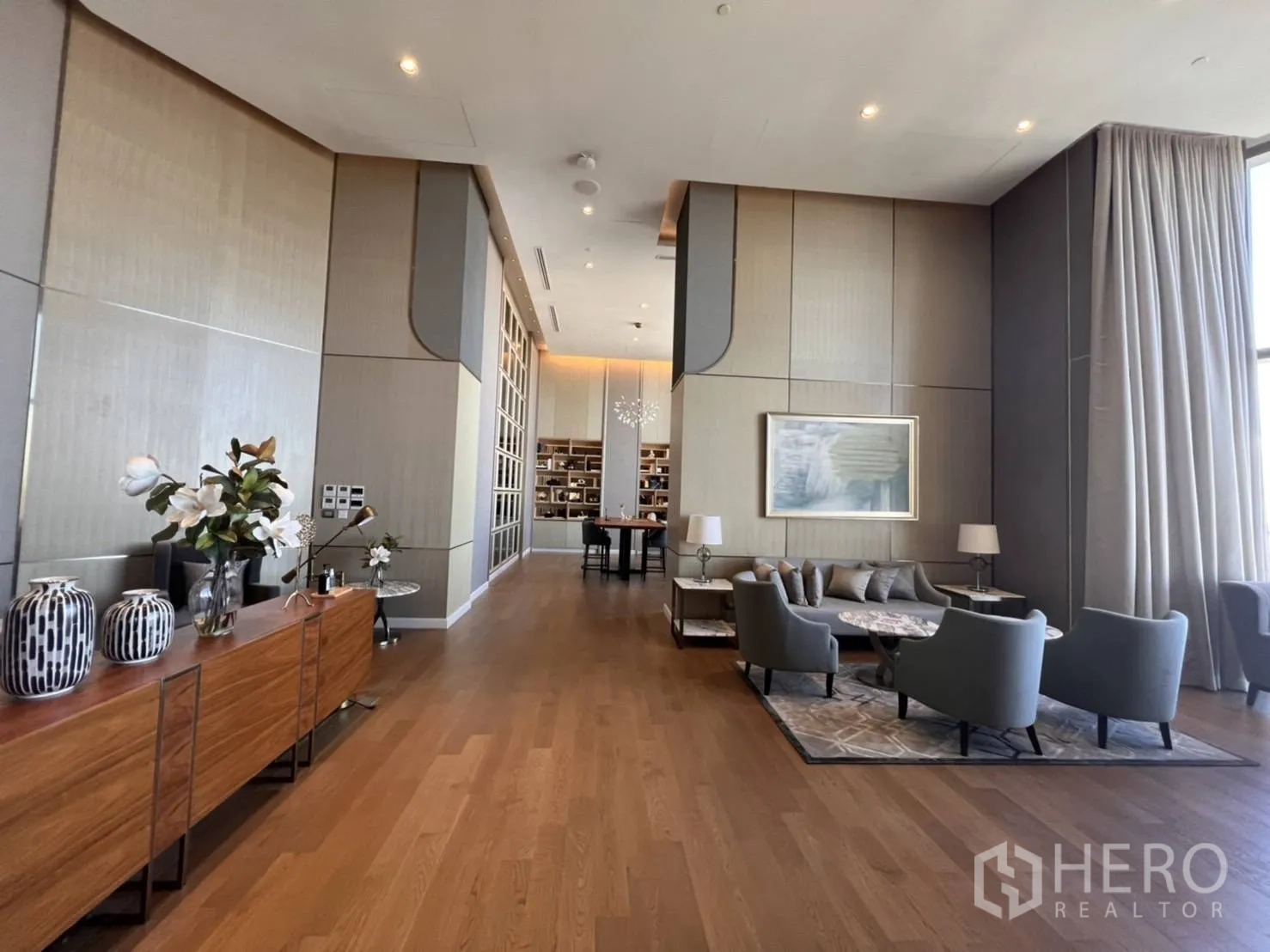 คอนโด for rent in Khlong San, Bangkok - เลานจ์ส่วนกลางเพดานสูง พื้นไม้ เฟอร์นิเจอร์โมเดิร์น ผ้าม่านทิ้งตัว และชั้นหนังสือ