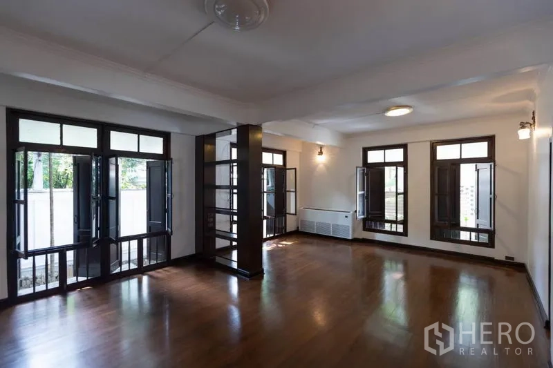 Detached House for rent in Pathum Wan, Bangkok - Bright family room with multiple French windows and polished wooden floors.