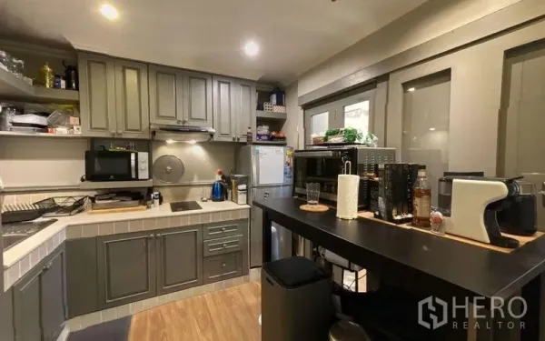 Condominium for sale in Watthana, Bangkok - Modern gray kitchen with built-in cabinets, cooktop, breakfast bar and appliances.