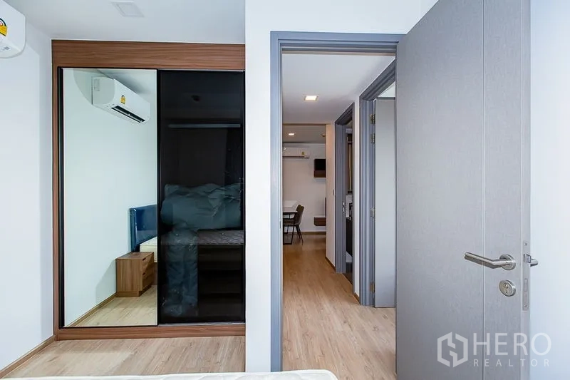 คอนโด ให้เช่าในWatthana, Bangkok - ทางเข้าห้องนอนพร้อมตู้เสื้อผ้าบานเลื่อนกระจกเงา พื้นไม้ มองไปยังโถงทางเดินและมุมทานอาหาร