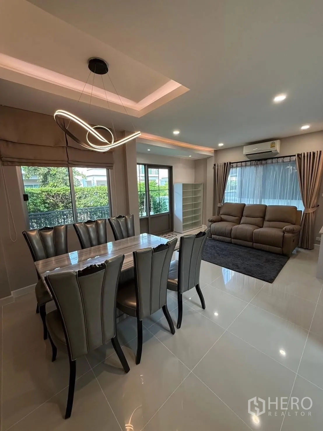 Detached House for rent in Prawet, Bangkok - Dining room with sculptural chandelier beside bright living area and garden views.