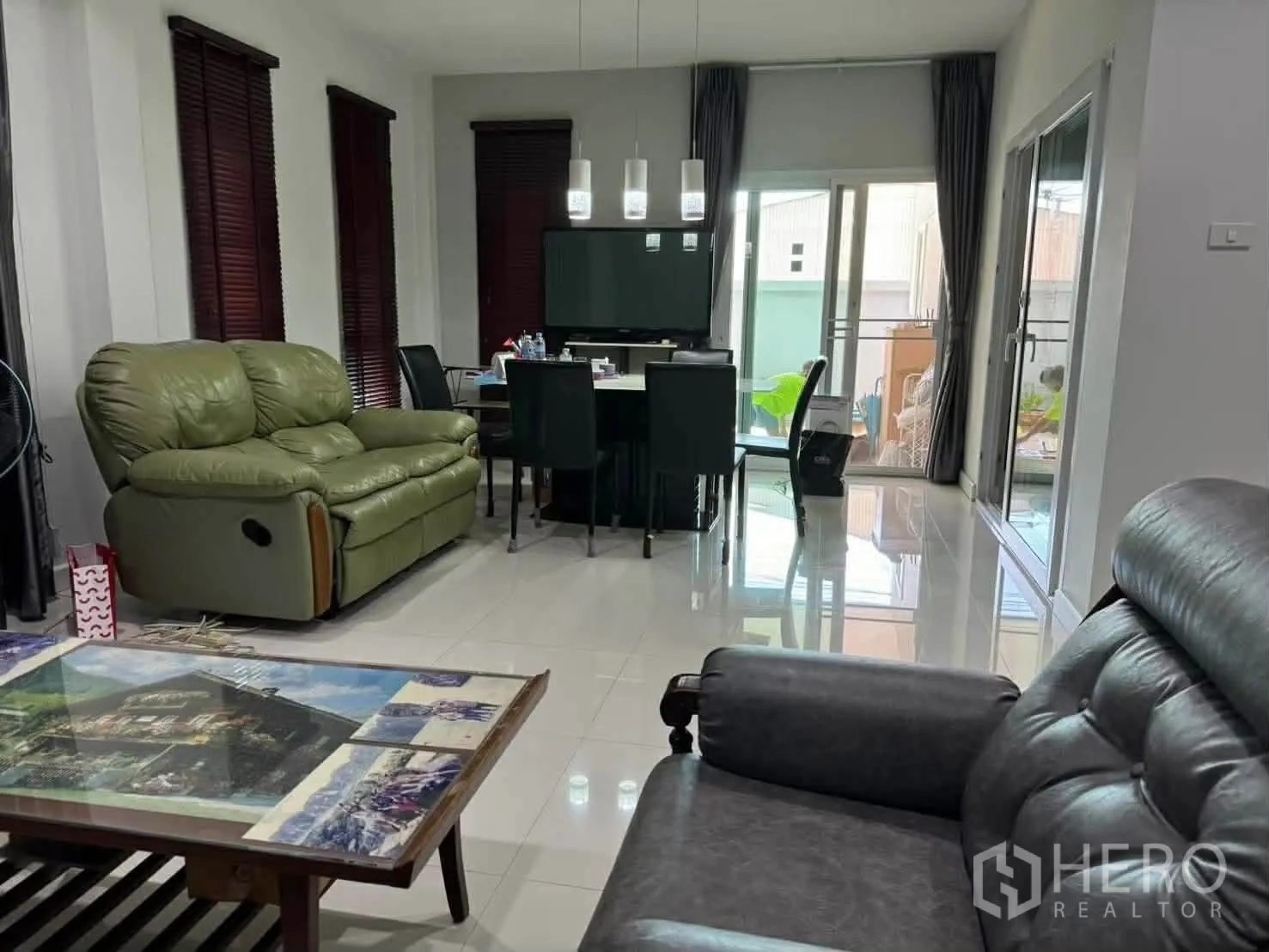 Detached House for rent in Watthana, Bangkok - Open-plan living and dining area with sofas, dining set, and sliding doors to the patio.