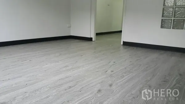 อาคารพาณิชย์ ให้เช่าในWatthana, Bangkok - ภาพระยะใกล้ของพื้นไวนิลลายไม้สีเทาอ่อนและบัวพื้นสีดำ.