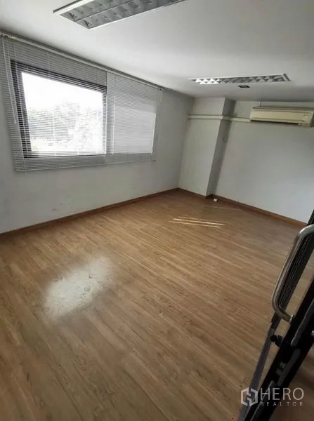 Home Office for rent in Prawet, Bangkok - Sunlit workspace with large window, blinds, and wooden flooring