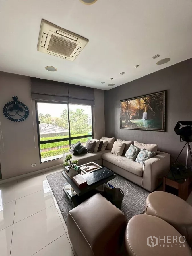 Detached House for sale in Bang Lamung, Chon Buri - Bright lounge with large window, sofa set and wall art.