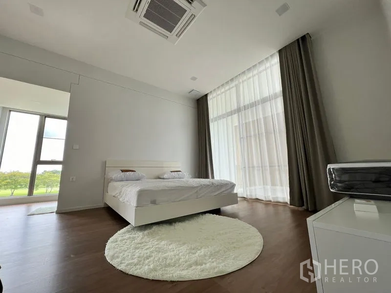 Detached House for rent or sale in Saphan Sung, Bangkok - Spacious bedroom with full‑height glazing, sheer curtains and wood floors.