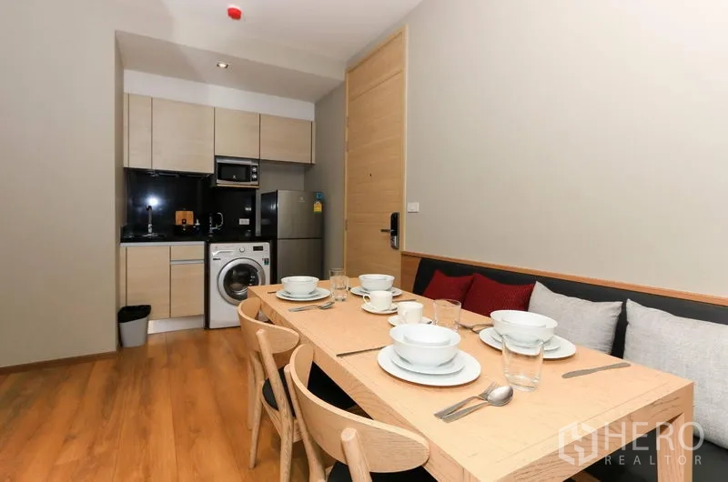 คอนโด ให้เช่าในKhlong Toei, Bangkok - โต๊ะทานอาหาร 6 ที่นั่งจัดวางจานชามอยู่ข้างครัวและประตูทางเข้า