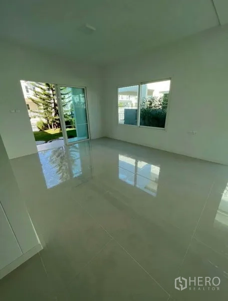 บ้าน ให้เช่าในMin Buri, Bangkok - ห้องนั่งเล่นสว่าง พื้นกระเบื้องเงา หน้าต่างบานใหญ่และประตูบานเลื่อนเปิดออกสู่สวน ในบ้านเดี่ยวมีนบุรี