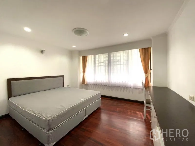 คอนโด ให้เช่าในWatthana, Bangkok - ห้องนอนพร้อมฐานเตียงคิง พื้นไม้ โต๊ะทำงานบิลท์อินยาว และหน้าต่างสว่างพร้อมผ้าม่านสีทอง