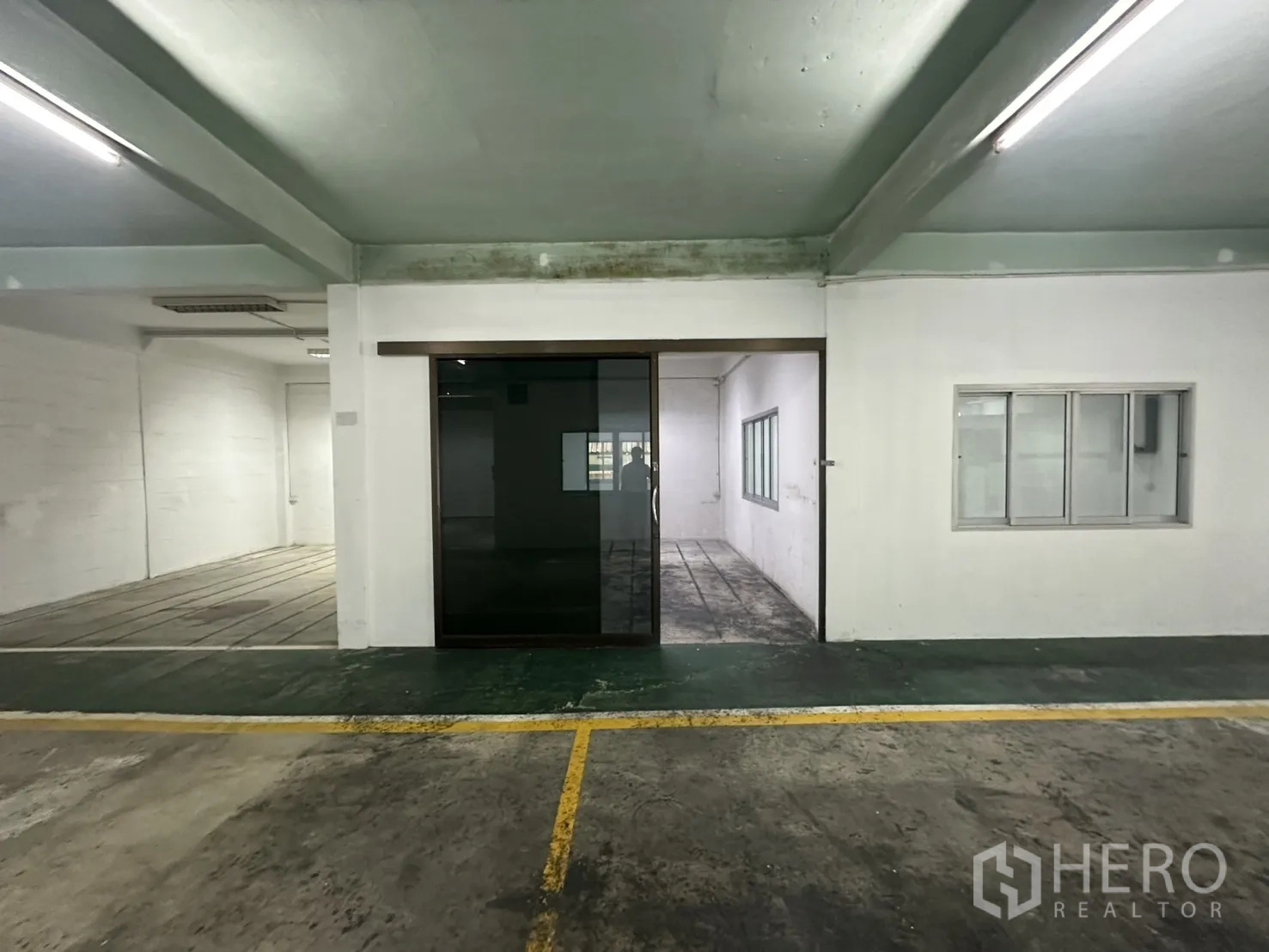 Warehouse for rent in Bang Na, Bangkok - Close-up of black-framed glass door and wall windows inside the warehouse.