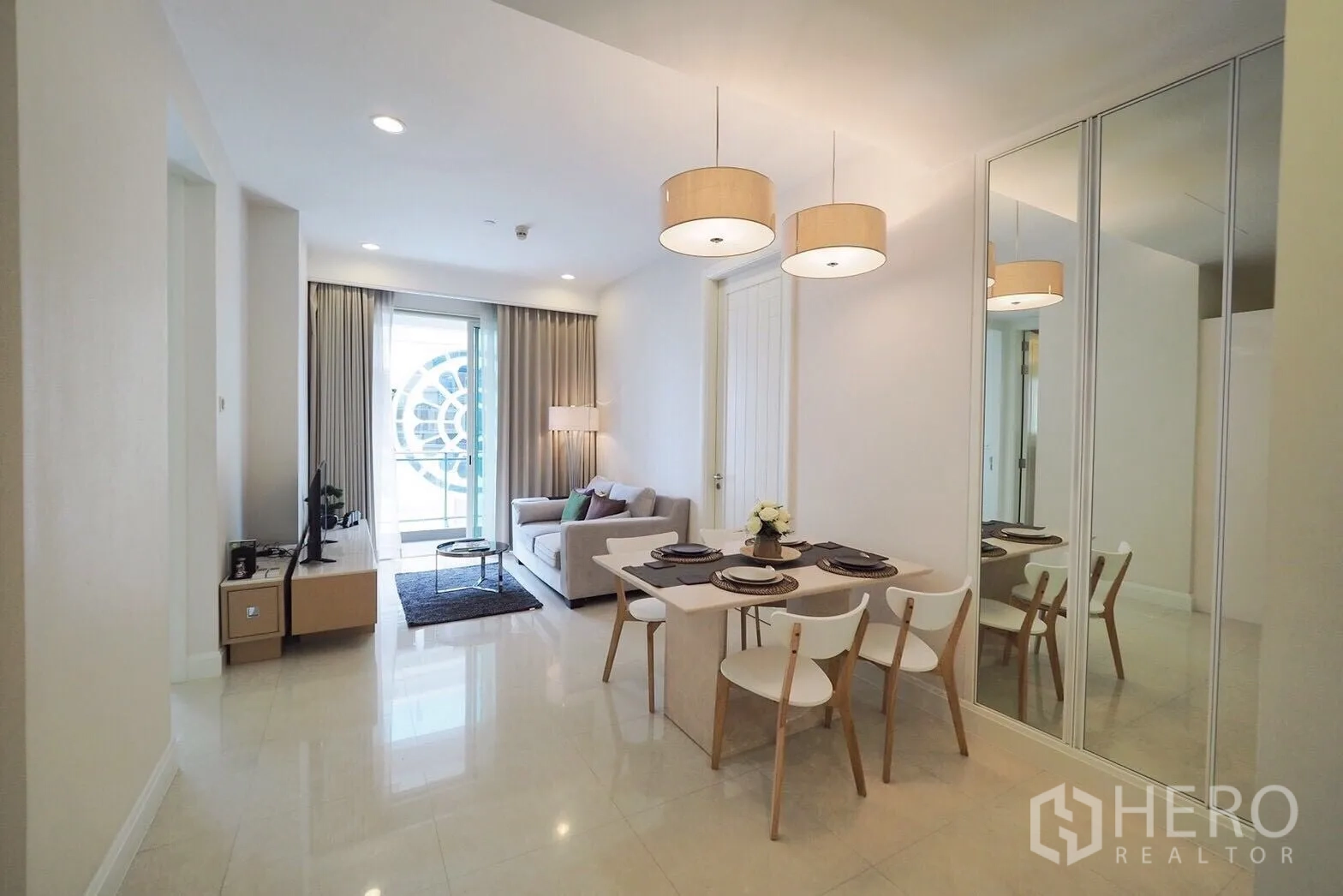 Condominium for rent in Pathum Wan, Bangkok - Open-plan living and dining area with pendant lights and balcony access.