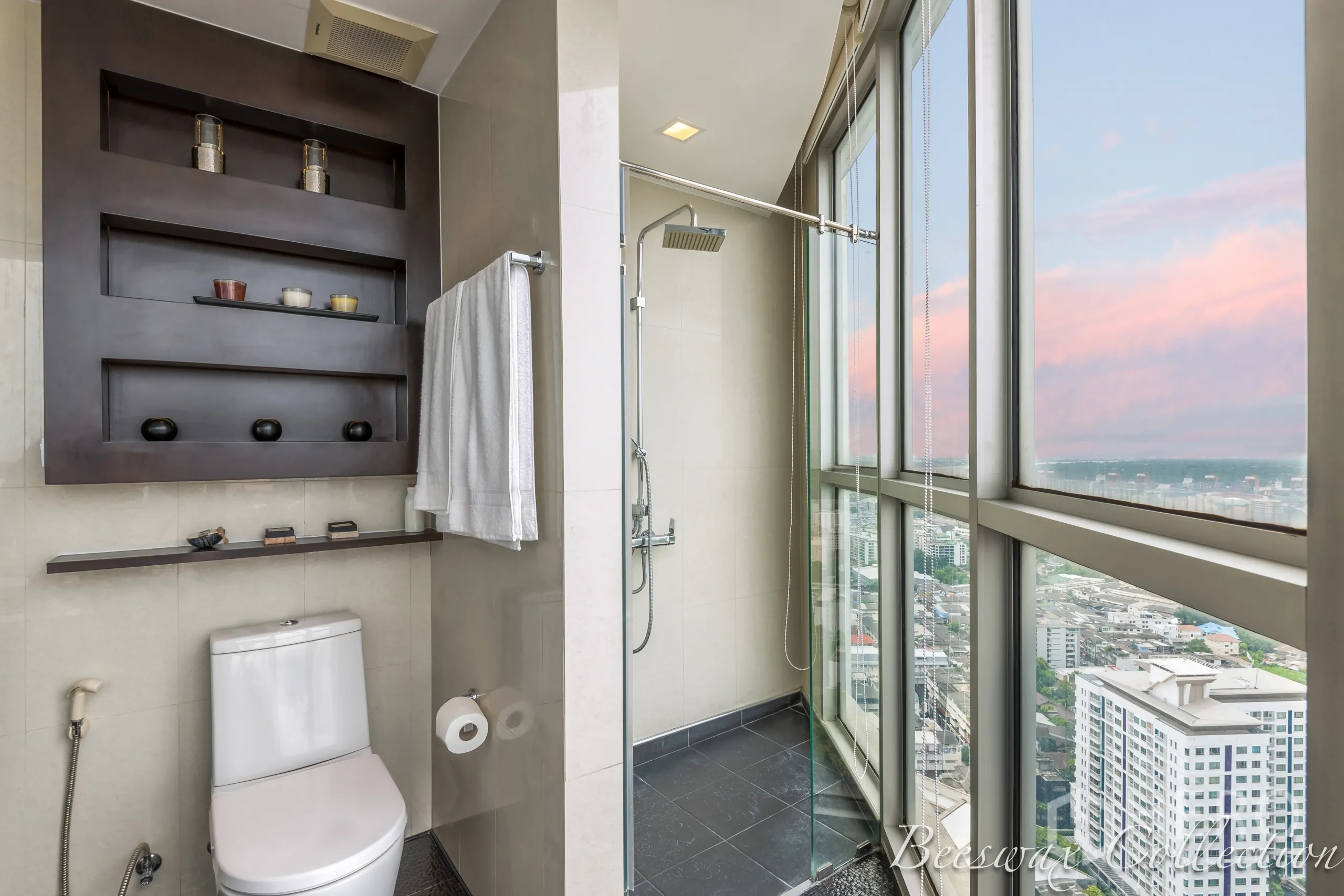 คอนโด ให้เช่าในWatthana, Bangkok - ห้องน้ำพร้อมฝักบัวแบบวอล์กอินติดหน้าต่างสูง เห็นวิวเมือง และมีชั้นวางของบิลท์อินเหนือโถสุขภัณฑ์