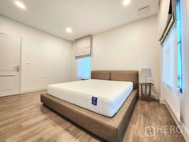 Detached House for rent in Saphan Sung, Bangkok - Bedroom from another angle with corner windows, bedside table and calm neutral tones.